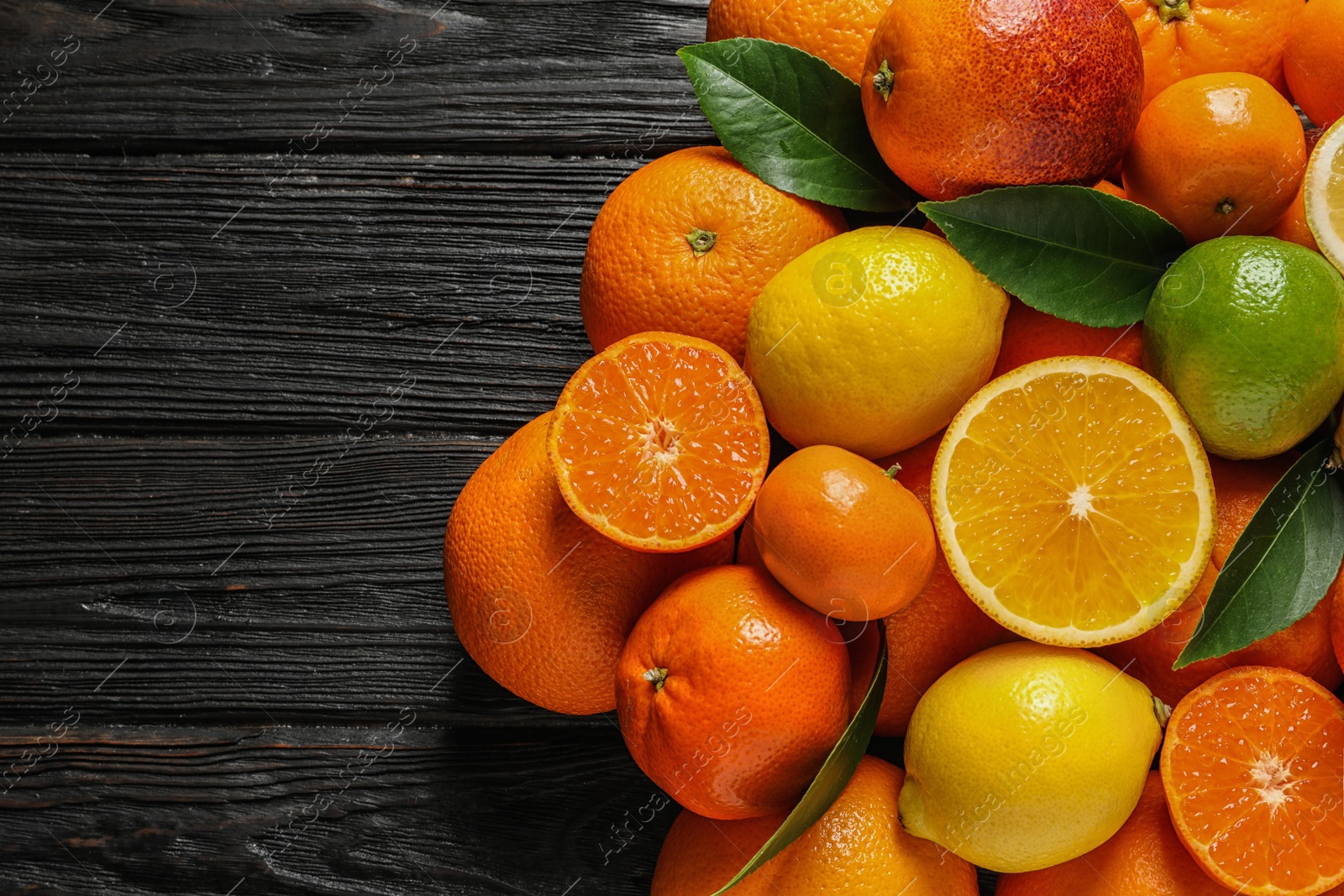 Photo of Different citrus fruits with leaves on wooden background, top view. Space for text