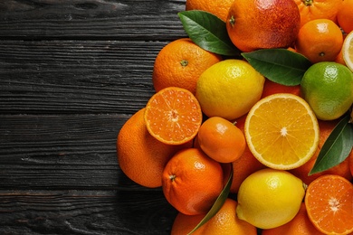 Photo of Different citrus fruits with leaves on wooden background, top view. Space for text