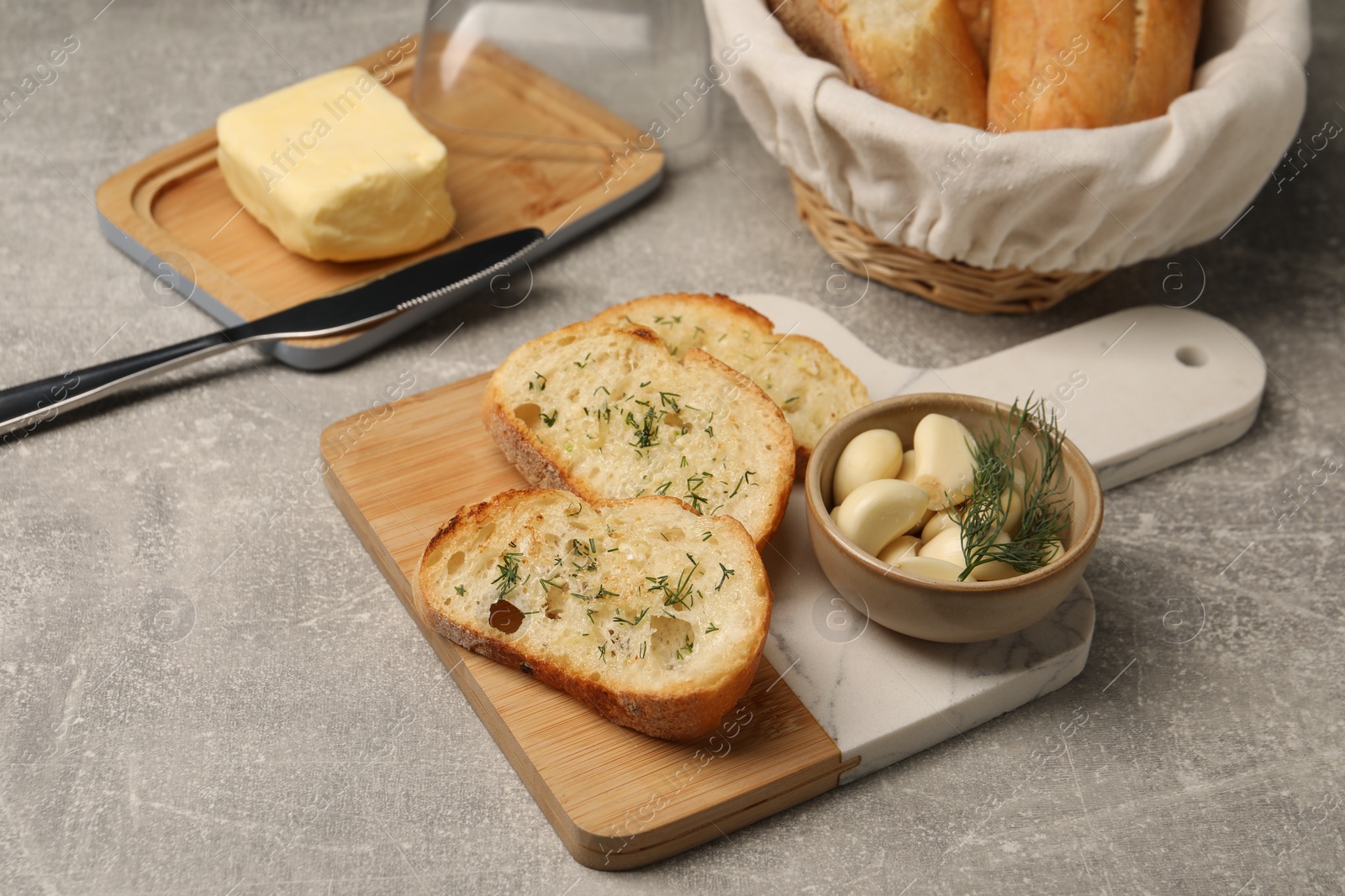 Photo of Tasty baguette with garlic and dill served on light grey table