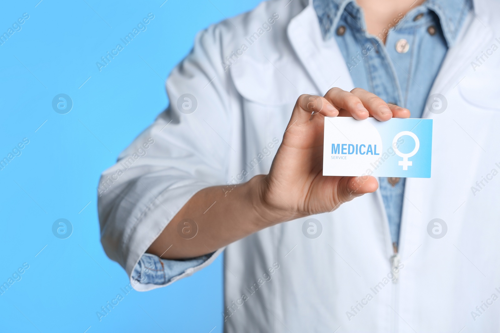 Photo of Doctor holding medical business card on color background, closeup. Women's health service