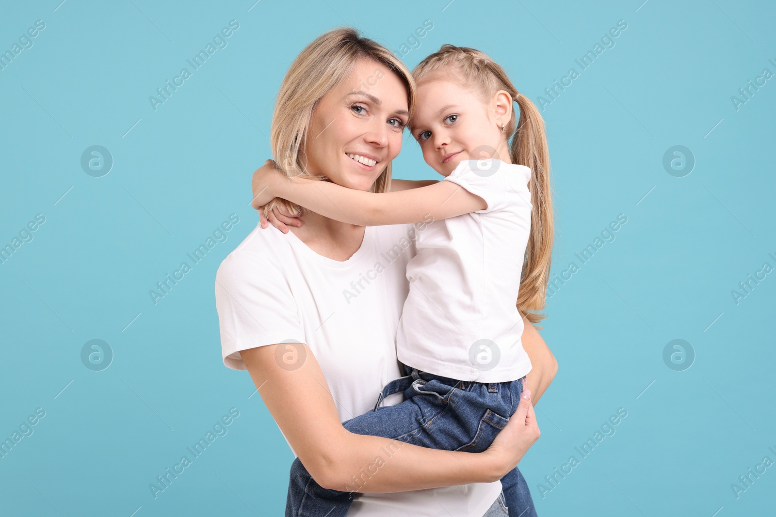 Photo of Family portrait of happy mother and daughter on light blue background