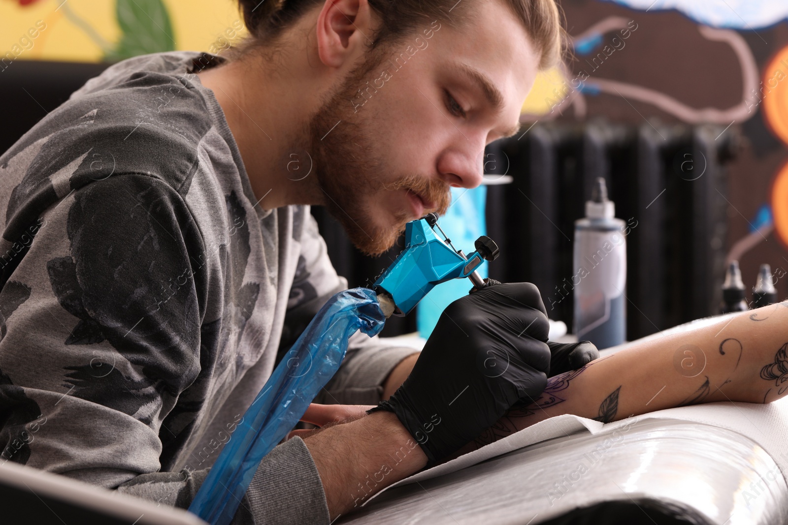 Photo of Professional artist making tattoo on hand in salon