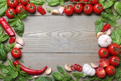 Frame made of fresh basil leaves and vegetables on wooden table, flat lay. Space for text