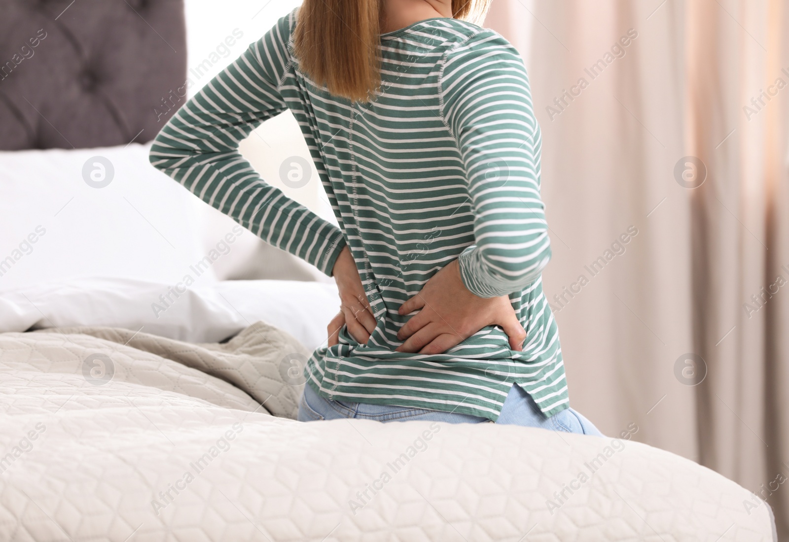 Photo of Young woman suffering from back pain at home, closeup