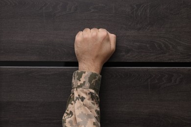 Military commissariat representative knocking on wooden door, closeup