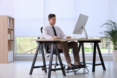 Photo of Man using footrest while working on computer in office