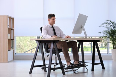 Man using footrest while working on computer in office