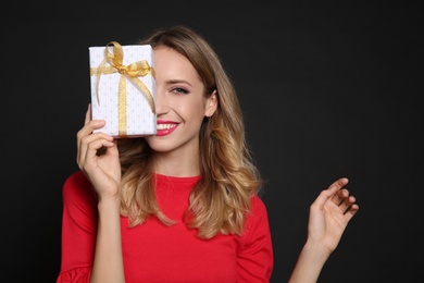 Happy woman with gift box on black background. Christmas party