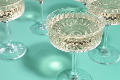 Photo of Glasses of expensive white wine on turquoise background, closeup
