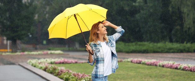 Image of Happy young woman with umbrella under autumn rain in park. Banner design