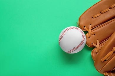 Photo of Catcher's mitt and baseball ball on green background, top view with space for text. Sports game