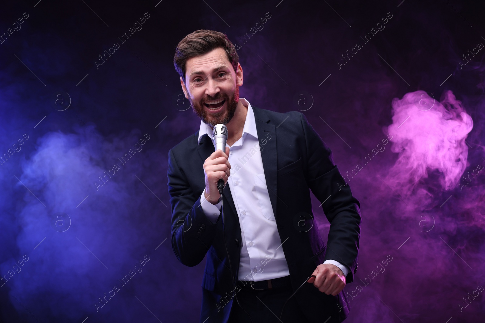 Photo of Emotional man with microphone singing in neon lights