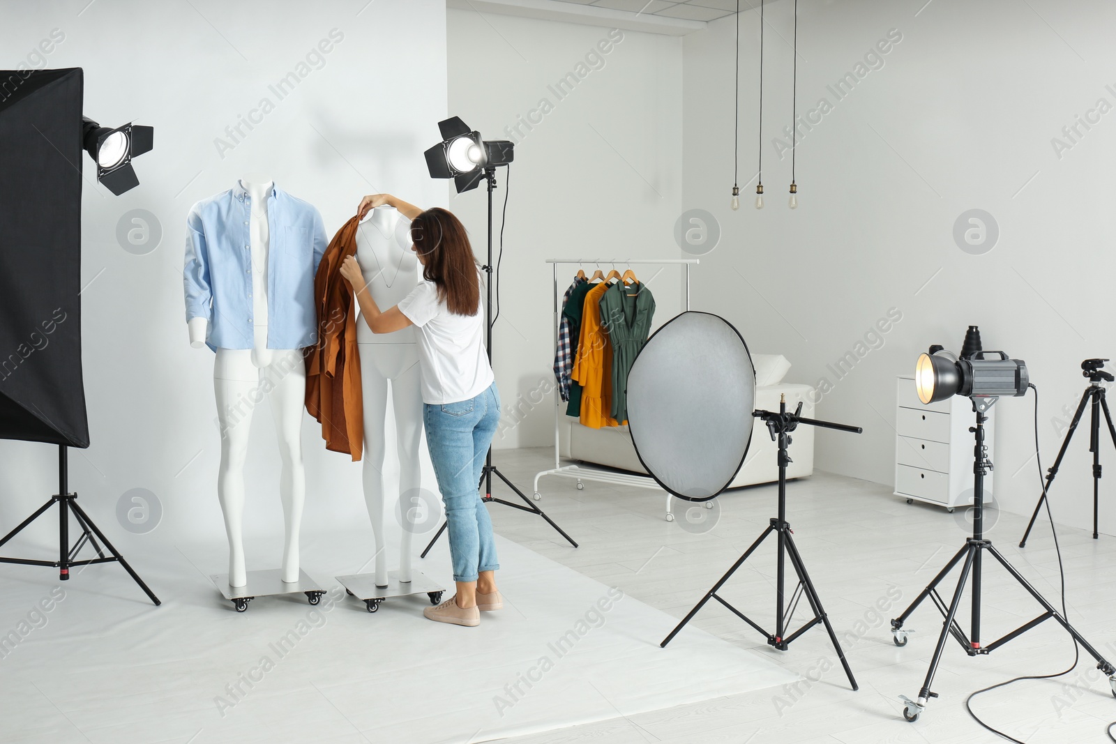 Photo of Woman putting clothes on ghost mannequins in professional photo studio