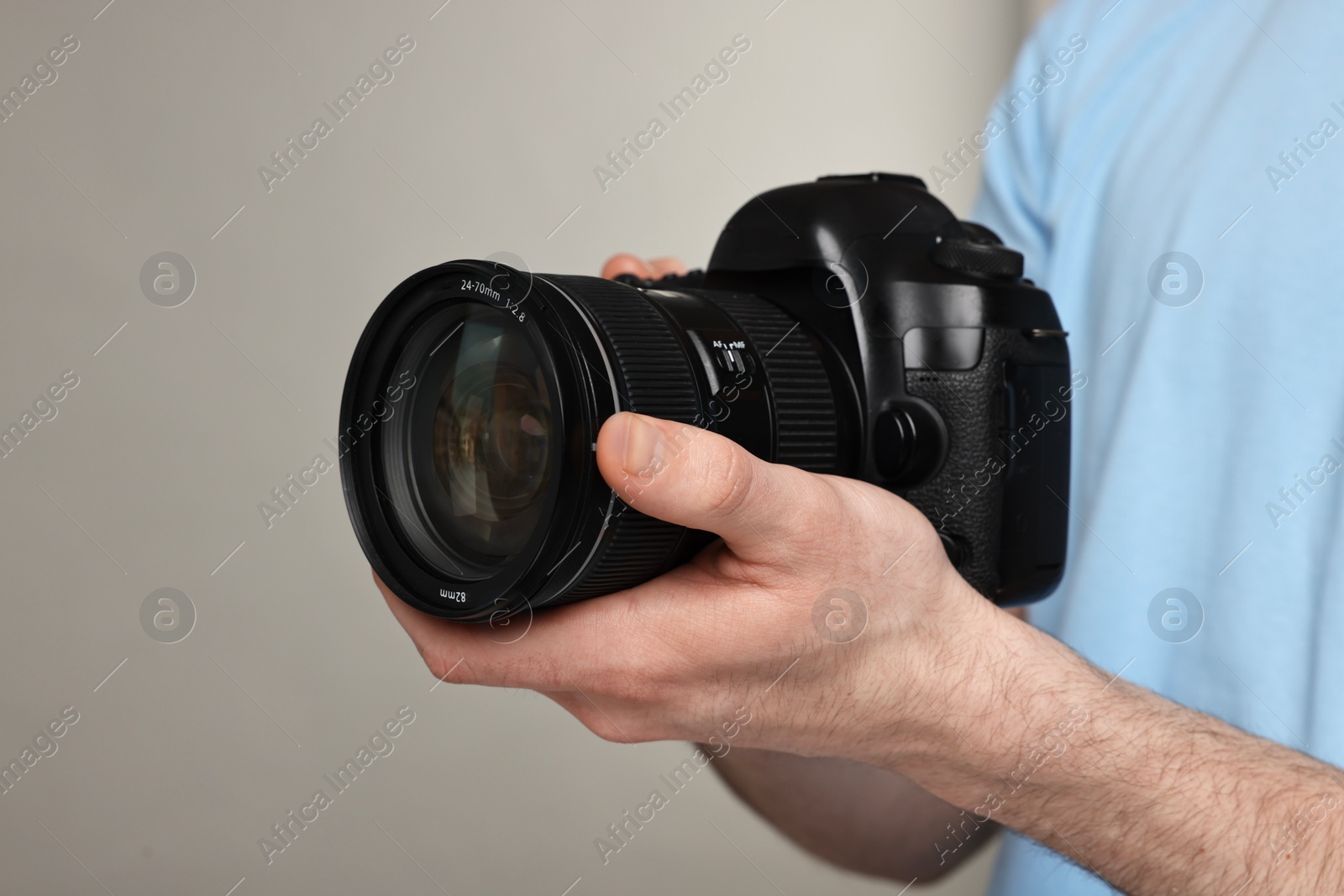 Photo of Photographer holding camera on grey background, closeup