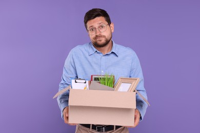 Photo of Unemployed man with boxpersonal office belongings on purple background