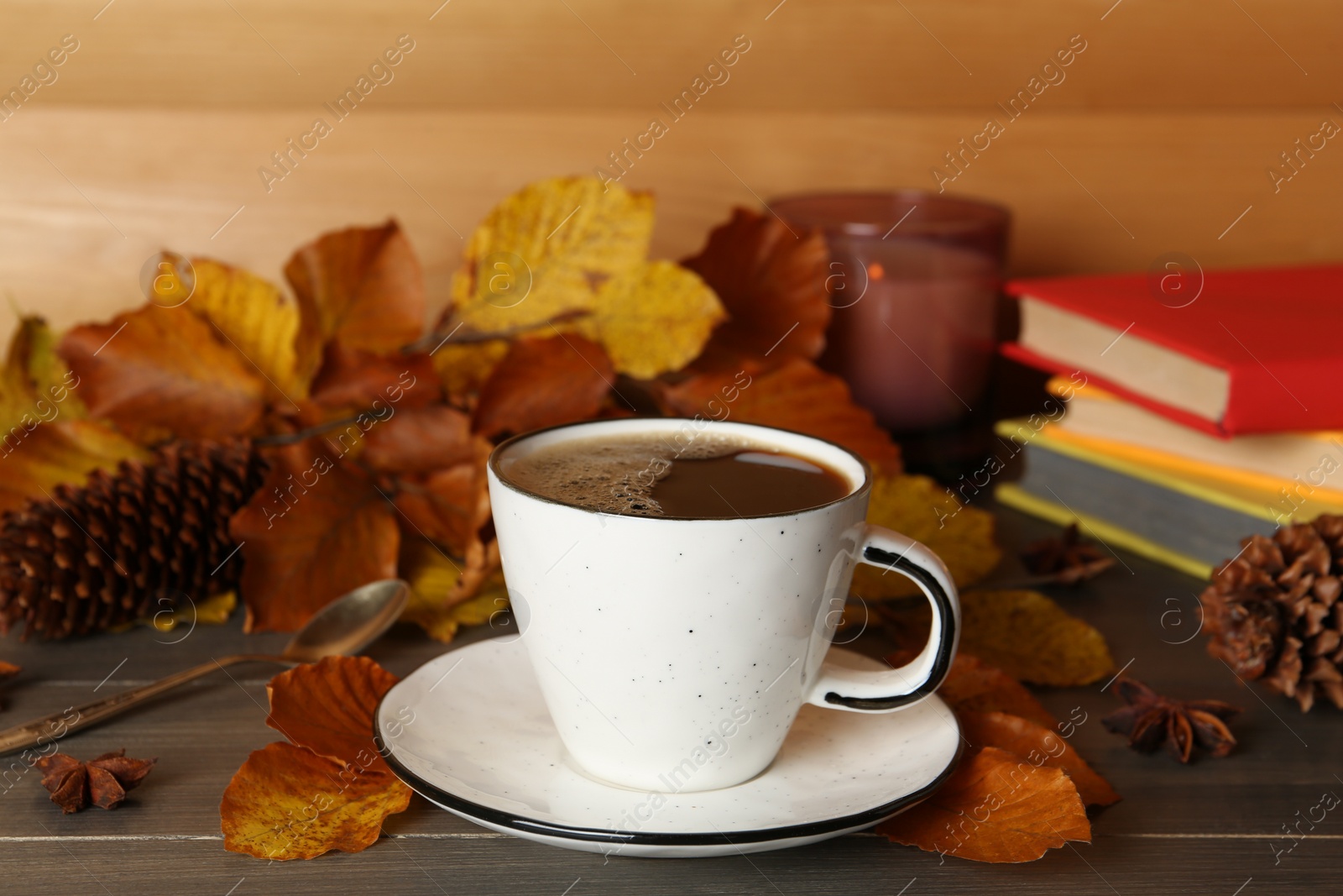 Photo of Composition with cup of hot coffee and autumn leaves on wooden table
