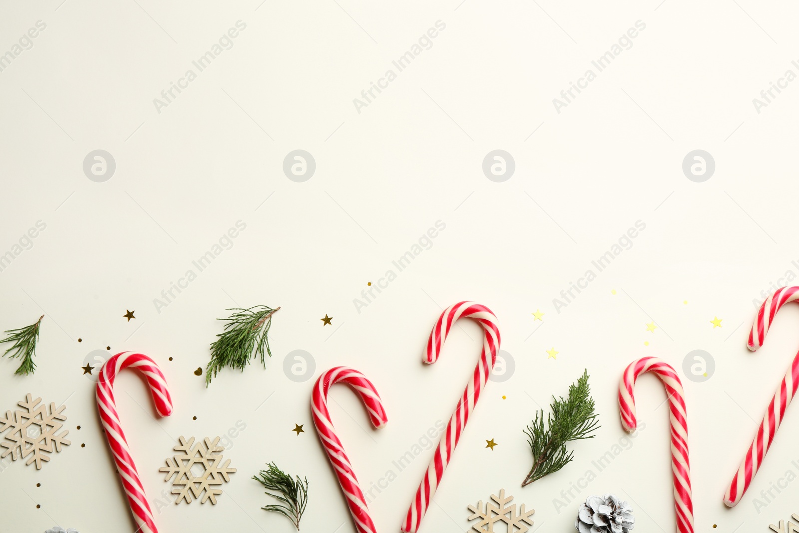 Photo of Flat lay composition with candy canes and Christmas decor on beige background. Space for text