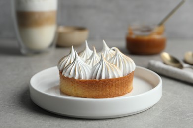 Photo of Tartlet with meringue on grey table, closeup. Delicious dessert