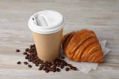 Coffee to go. Paper cup with tasty drink, croissant and beans on white wooden table