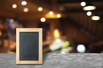 Blank small blackboard on wooden table in cafe, mockup for menu design 