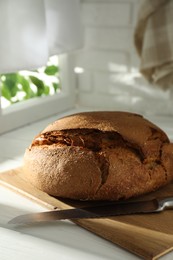 Photo of Freshly baked sourdough bread on white wooden table indoors