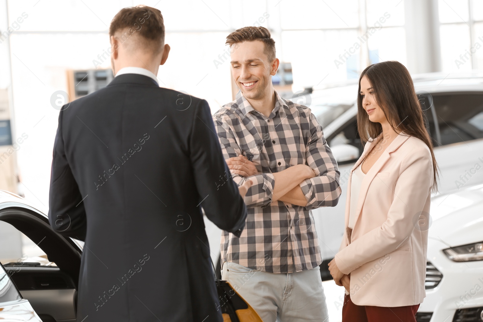 Photo of Young couple buying new car in salon