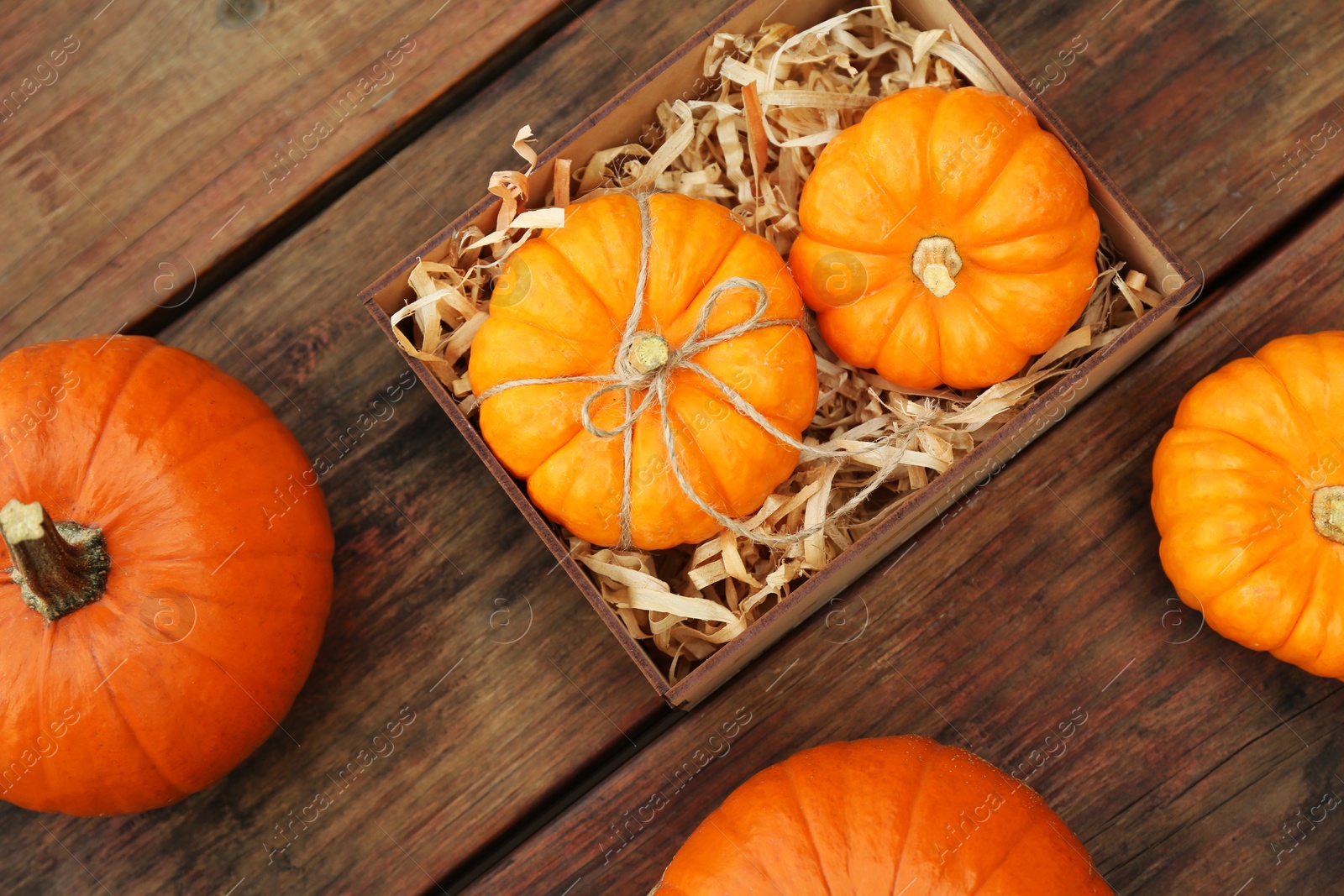 Photo of Crate and ripe pumpkins on wooden table, flat lay