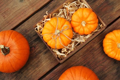 Photo of Crate and ripe pumpkins on wooden table, flat lay