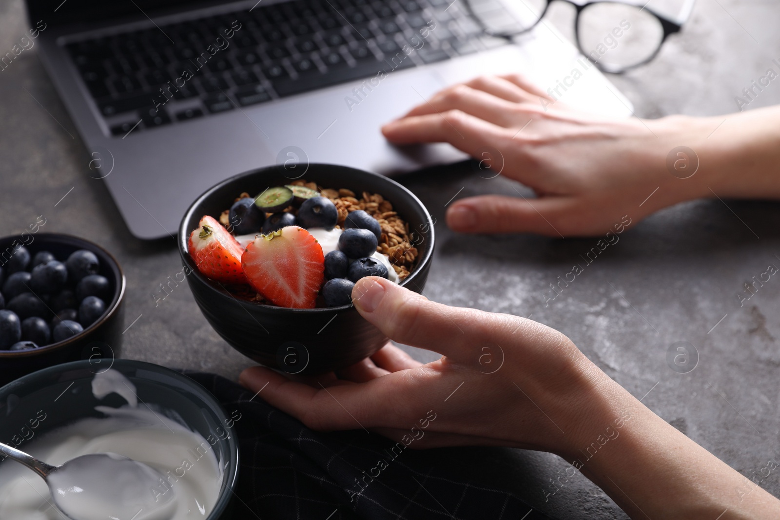 Photo of Woman with tasty granola at workplace, closeup