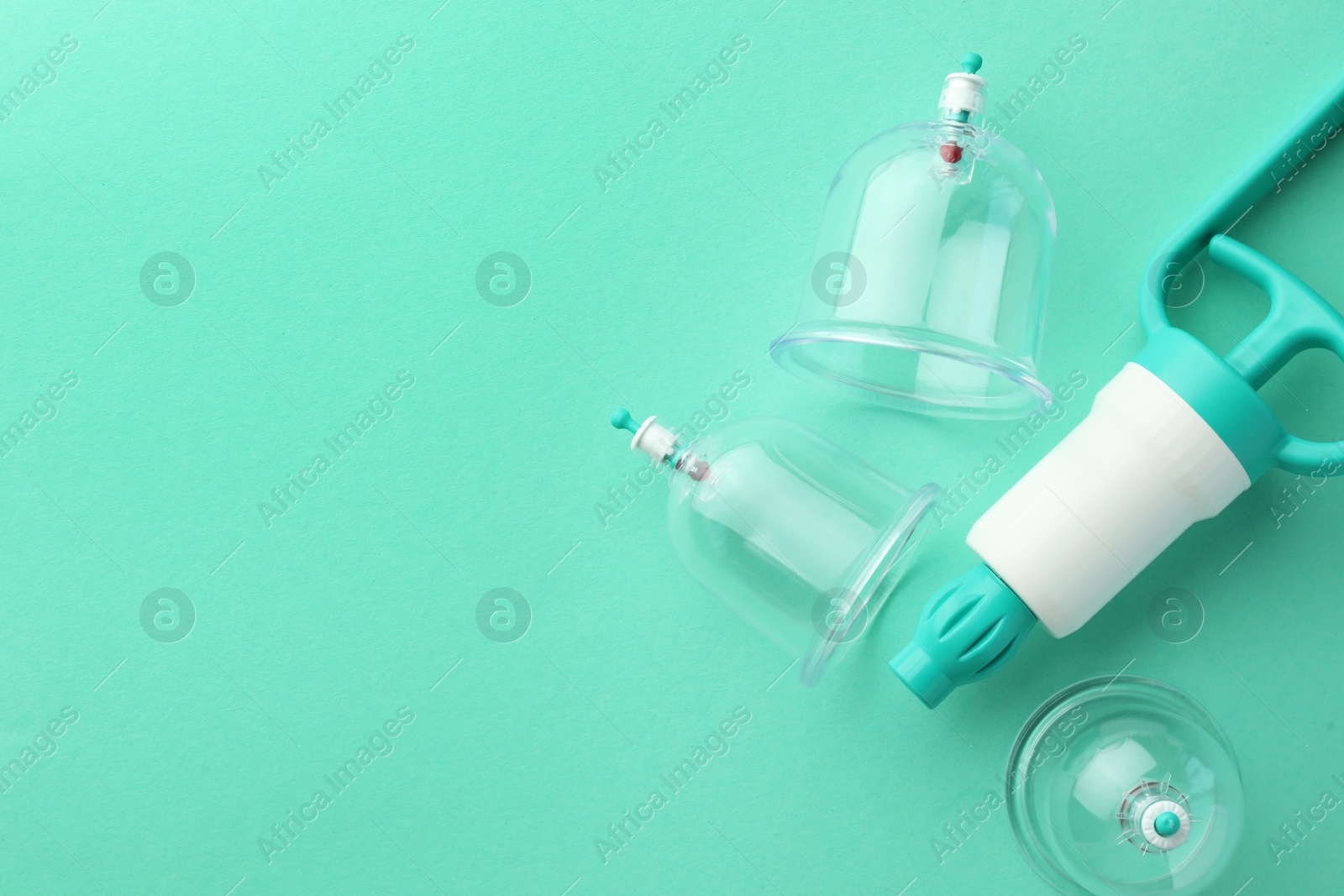 Photo of Plastic cups and hand pump on turquoise background, flat lay with space for text. Cupping therapy