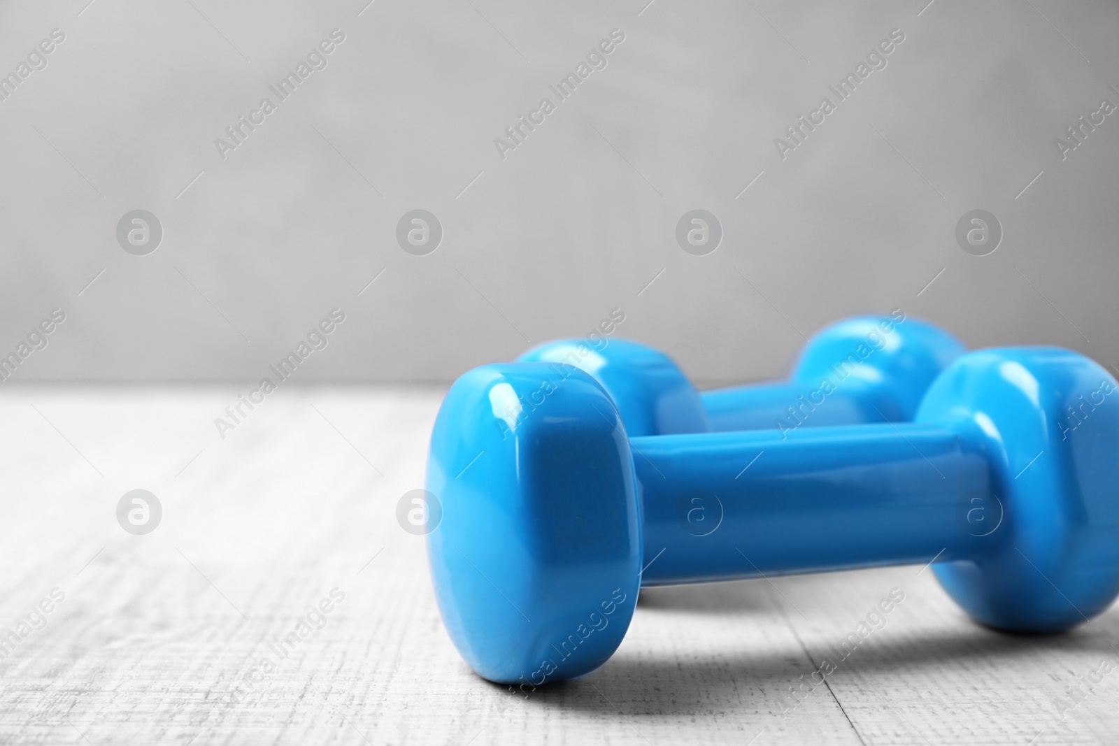 Photo of Color dumbbells on wooden floor, space for text. Home fitness
