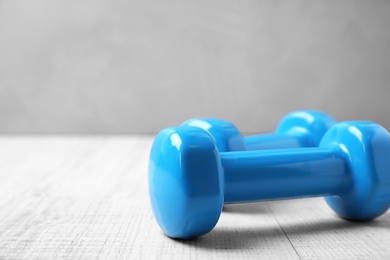 Color dumbbells on wooden floor, space for text. Home fitness