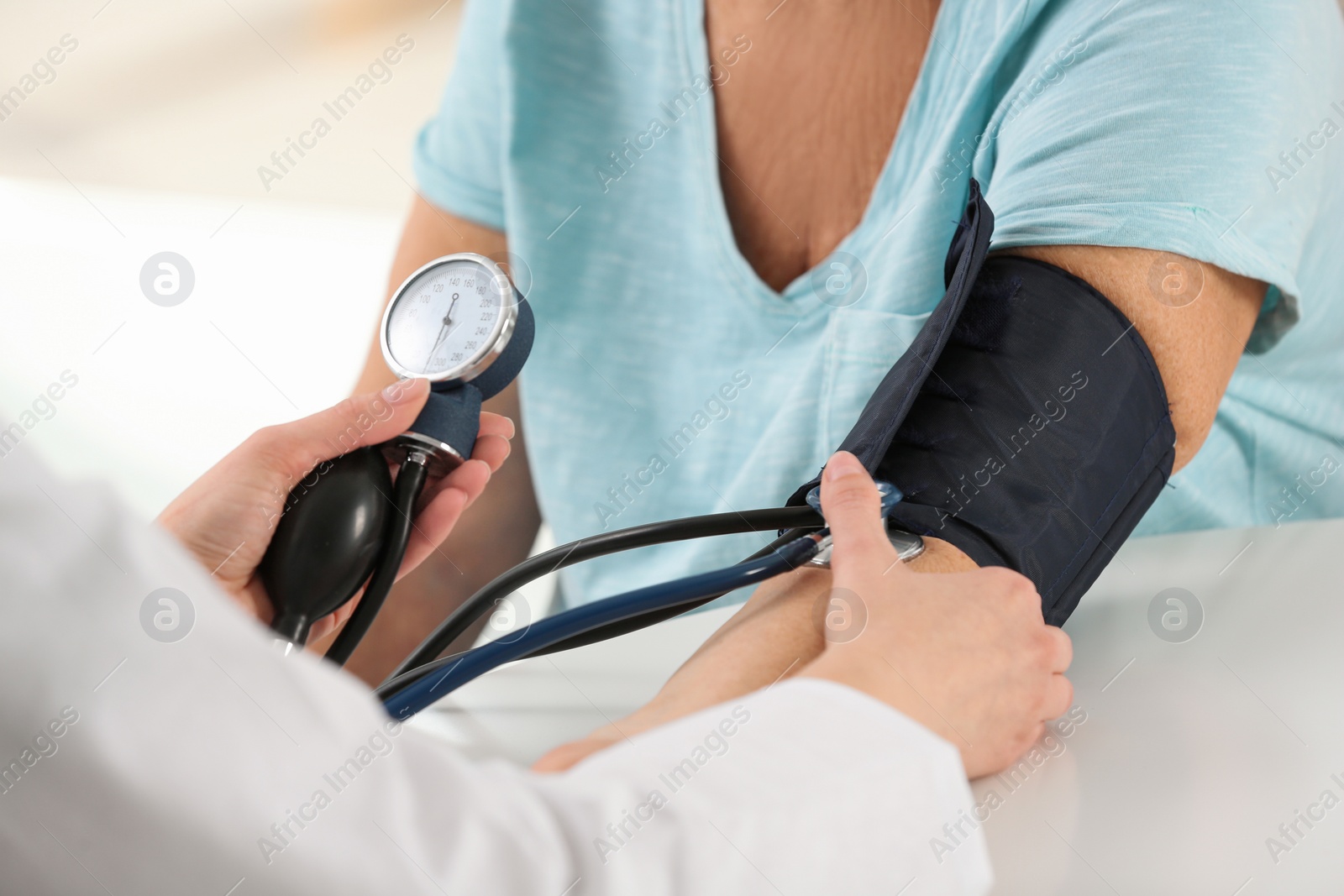 Photo of Nurse measuring blood pressure of elderly woman at table, closeup. Assisting senior generation