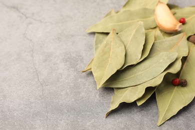 Photo of Aromatic bay leaves and spices on light gray table, closeup. Space for text