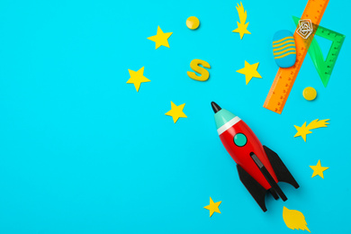 Photo of Bright toy rocket and school supplies on light blue background, flat lay. Space for text