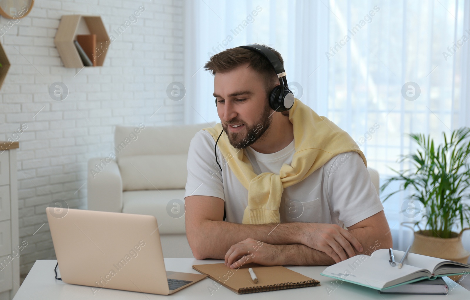 Photo of Young man watching online webinar at table indoors