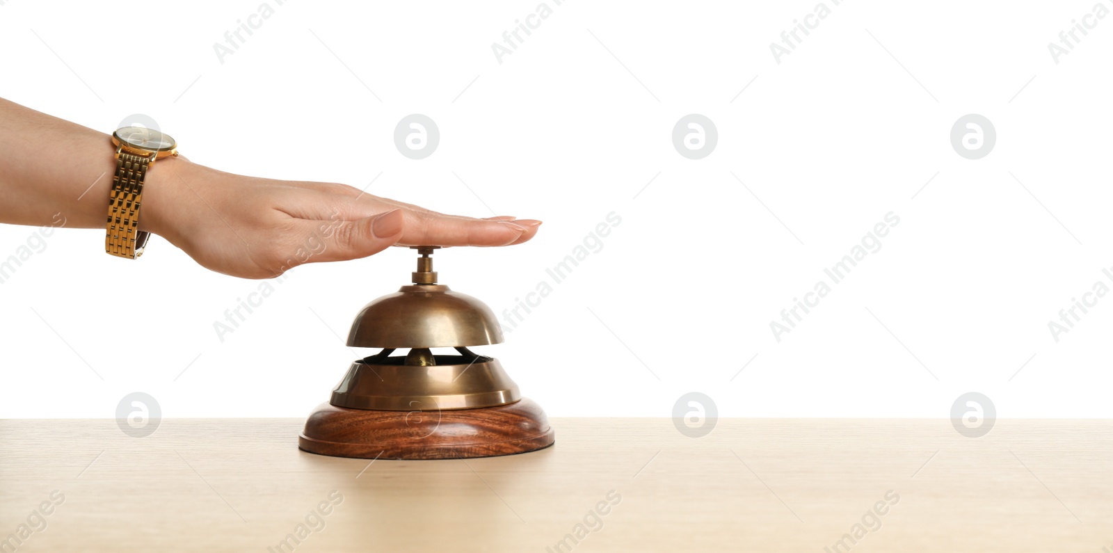 Photo of Woman ringing hotel service bell at wooden table