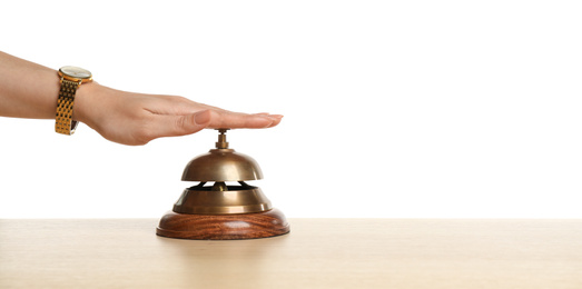 Photo of Woman ringing hotel service bell at wooden table