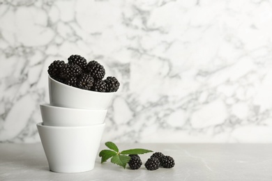 Photo of Bowl of fresh blackberry on table against marble background. Space for text