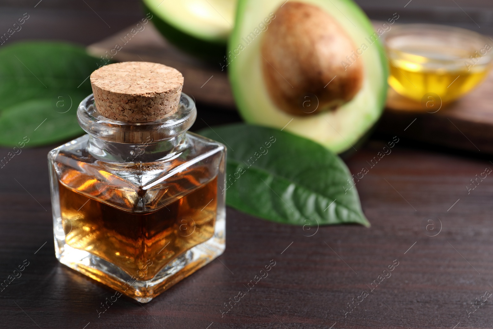 Photo of Bottle of avocado essential oil on wooden table. Space for text