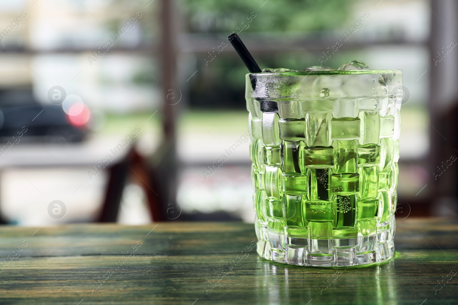 Photo of Glass of delicious cocktail with ice on table in bar