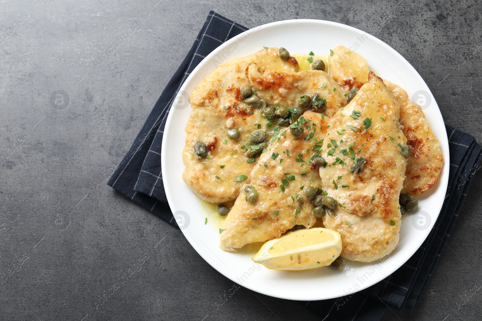 Photo of Delicious chicken piccata with herbs on grey table, top view. Space for text