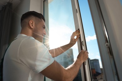 Man putting rubber draught strip onto window indoors