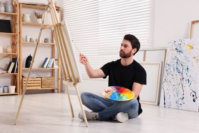 Man painting in studio. Using easel to hold canvas