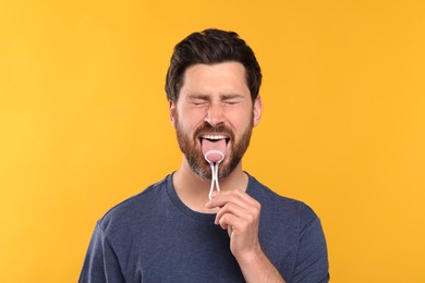 Photo of Handsome man brushing his tongue with cleaner on yellow background