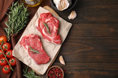 Photo of Fresh raw meat with rosemary, tomatoes and spices on wooden table, flat lay. Space for text