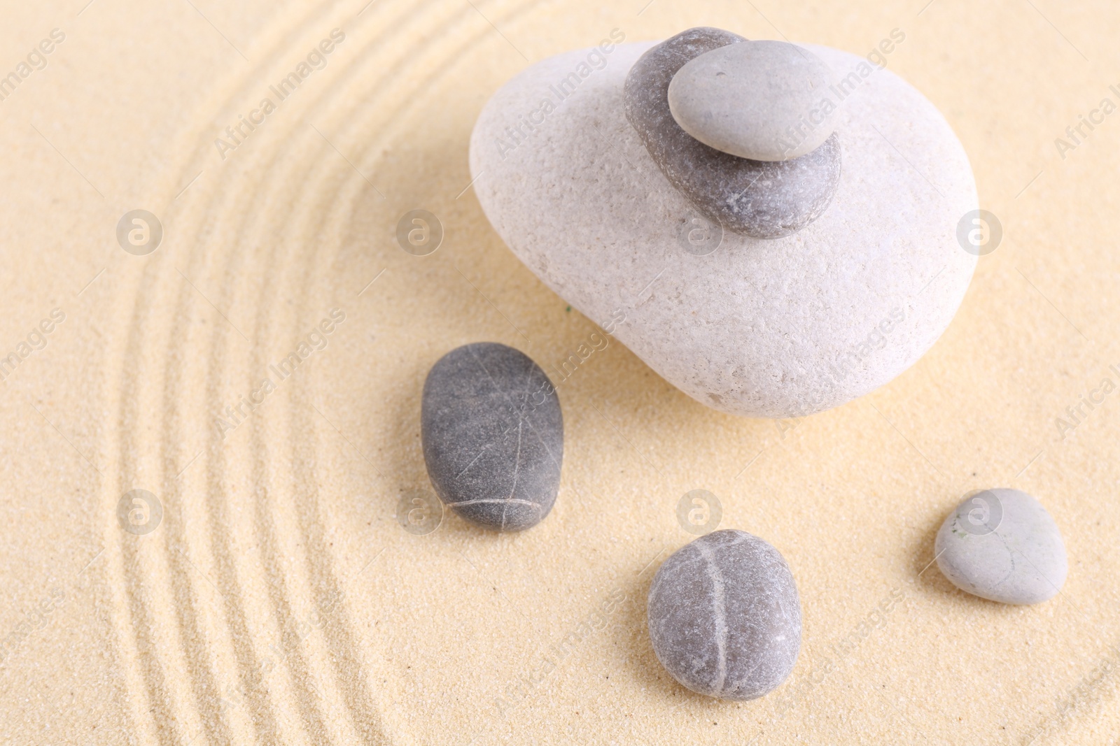 Photo of Zen garden stones on sand with pattern. Space for text