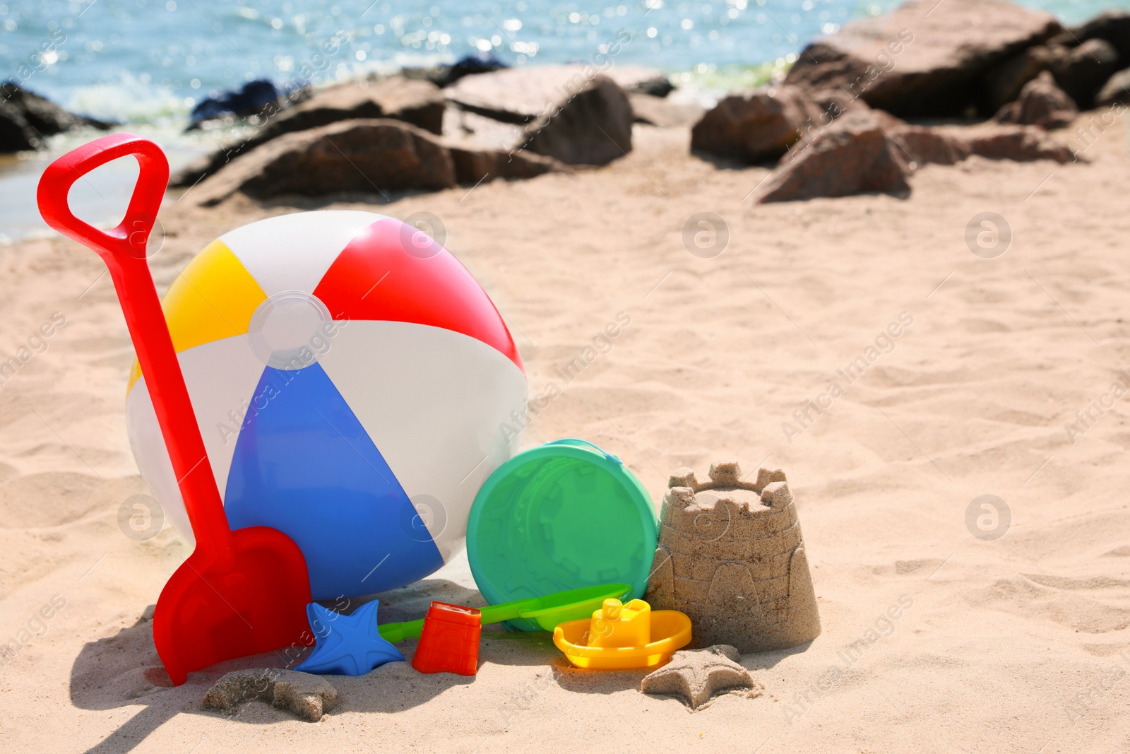 Photo of Different sand toys and beach ball near sea