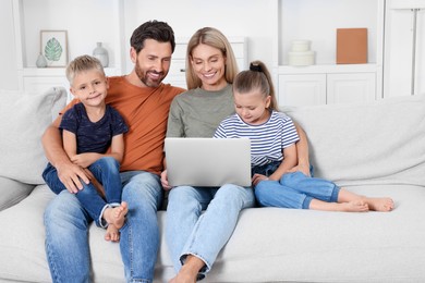 Happy family with laptop spending time together on sofa at home