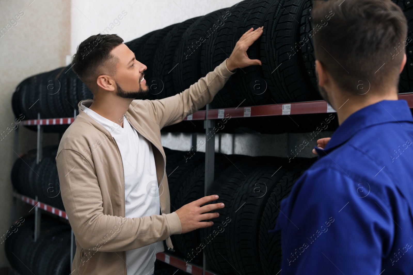 Photo of Mechanic helping client to choose car tire in auto store